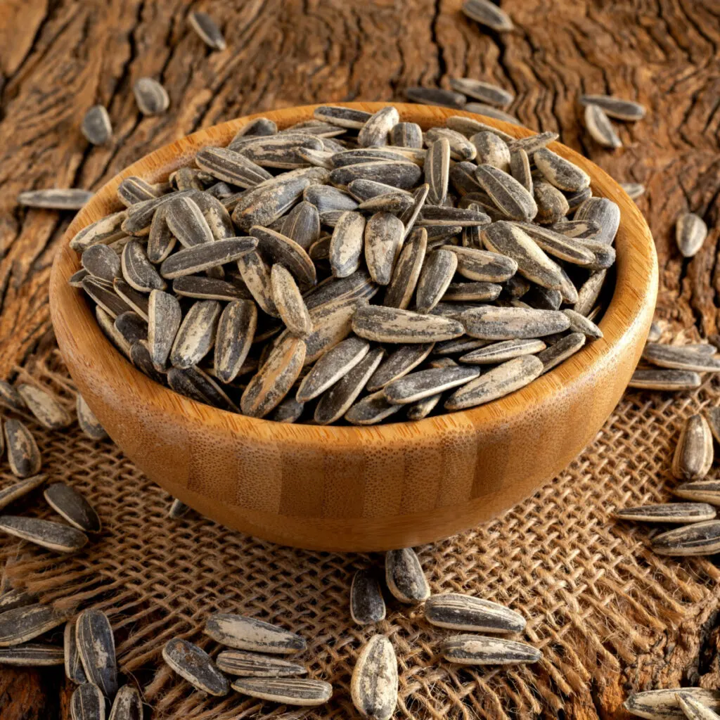 A wooden bowl holding roasted sunflower seeds